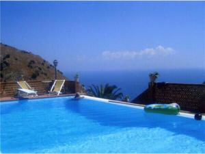 a large swimming pool with a view of the ocean at Luxury Suite terrazze e vista mare in Taormina