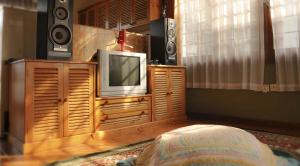 a tv sitting on a wooden entertainment center with speakers at Villa Kota Bunga Ade Type Jepang - 0228 in Cibadak