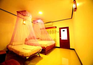 a bedroom with two beds with mosquito nets at Yuthika Resort in Negombo