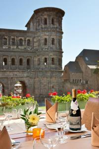 a table topped with a glass of wine and a vase filled with flowers at Mercure Hotel Trier Porta Nigra in Trier