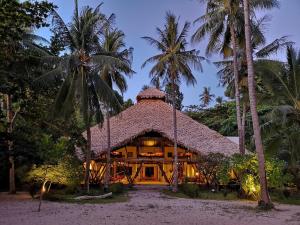 une maison sur la plage avec des palmiers dans l'établissement Coral Eye Boutique Resort and Marine Outpost, à Likupang