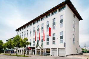 a white building with red flags on it at ibis Hotel München Garching in Garching bei München