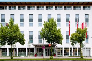 a white building with trees in front of it at ibis Hotel München Garching in Garching bei München