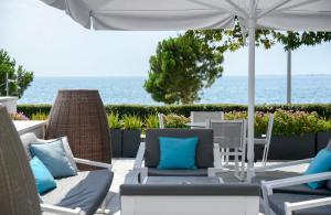 a patio with chairs and an umbrella and the ocean at Makedonia Palace in Thessaloniki