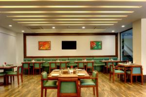 un restaurant avec des tables en bois et des chaises vertes dans l'établissement Lemon Tree Hotel, Katra, à Katra