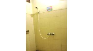 eine Dusche mit Schlauch in einem weiß gefliesten Badezimmer in der Unterkunft Villa Kota Bunga Ade Type Jepang - 0620 in Cibadak + 7 Fotos