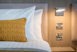 a bed with white sheets and a yellow pillow at Maldron Hotel Belfast City in Belfast