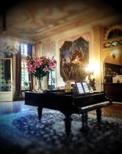 a piano in a room with flowers and a painting at Hotel Villa Condulmer in Mogliano Veneto