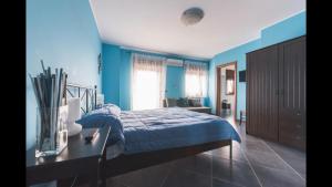 B&B Terrazza dell'Etna في ماسكالوتشا: غرفة نوم زرقاء مع سرير ومكتب