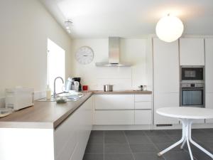 una cocina con armarios blancos y un reloj en la pared en Beautiful Ardennes house in quiet area en Sainte-Ode