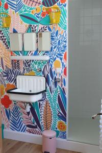 a bathroom with a colorful wallpaper with a sink at Le Petit Rivage in La Charité-sur-Loire