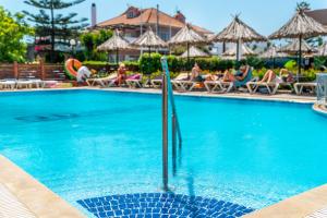 a swimming pool at a resort with people sitting in chairs at Sunday Hotel in Ialyssos