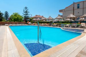 una piscina en un complejo con sillas y sombrillas en Sunday Hotel, en Ialisos