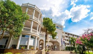 a large white building with trees in front of it at Hotel Malin in Malinska