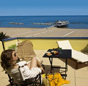 a woman sitting in a chair next to a table at Hotel Cavalluccio Marino in Gabicce Mare