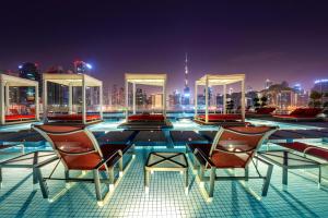 a pool with chairs and a city skyline at night at Canal Central Hotel Business Bay in Dubai