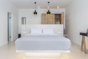 a white bedroom with a large bed with white sheets at Psaravolada Hotel Milos in Agia Kiriaki Beach