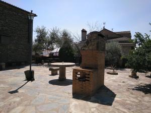 a brick fireplace and a picnic table in a courtyard at Casa Rural Peña Falcón in Torrejón el Rubio