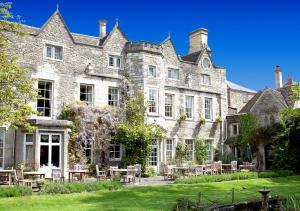 un ancien château avec des tables et des chaises devant lui dans l'établissement The Close Hotel, à Tetbury