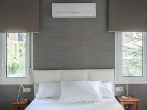 a bedroom with a white bed with two windows at El jardí de l'avet in Lleida