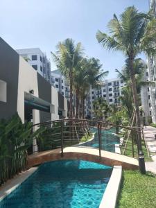 un pont sur une piscine bordée de palmiers et de bâtiments dans l'établissement Arcadia Beach Resort By Dary, à Pattaya (sud)