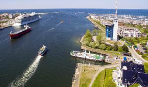 ein Boot in einem Fluss mit einem Kreuzfahrtschiff in der Unterkunft Ferienhaus der kurzen Wege Objekt 40105 in Warnemünde