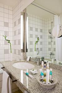 a bathroom with a sink and a mirror at Mercure Hotel am Messeplatz Offenburg in Offenburg