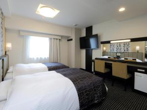 a hotel room with two beds and a desk at APA Hotel Nagoya Sakae Kita in Nagoya