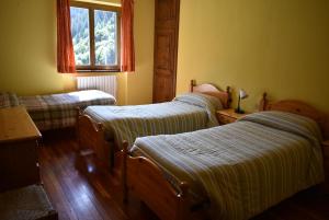 a bedroom with three beds and a window at Albergo Mangusta in Madesimo