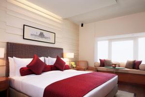 a bedroom with a large bed with red pillows at Taj Coromandel in Chennai