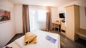 a hotel room with a bed and a desk at City-Hotel garni in Neu Ulm