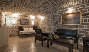 a living room with chairs and a couch in a stone wall at Hotel Azimut in Sveti Stefan