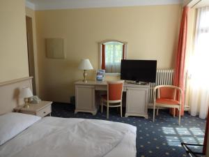 a hotel room with a bed and a desk with a computer at Hotel Schweizerhof in Weggis