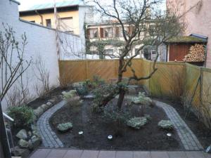 einen Garten vor einem Zaun mit einem Baum in der Unterkunft Iwan Ferienwohnungen Objekt 26001 in Warnemünde