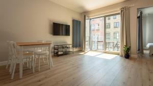 ein Wohnzimmer mit einem Tisch und Stühlen sowie einem großen Fenster in der Unterkunft VIU Old Town Balcony in Danzig