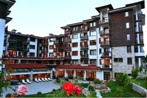 a large apartment building with a courtyard with red flowers at Top Apartment in Bansko in Bansko