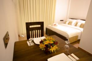 a bedroom with a bed and a table with flowers on it at Grand Casa in Kandy