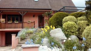 a garden in front of a house with blue flowers at Marcia Donatti-A l'Ombre des Coteaux Rio de Janeiro in Kaysersberg