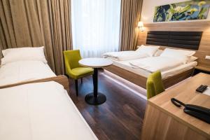 a hotel room with two beds and a table and chairs at Hotel Marc Aurel - Vienna City Center in Vienna