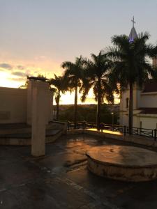 a sunset in a parking lot with palm trees at Galeria Park Hotel in Itápolis