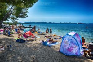 een groep mensen op een strand met een tent bij Bozena in Zadar