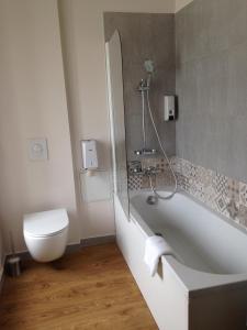 a white bath tub sitting next to a white toilet at Hôtel De L'Europe in Morlaix