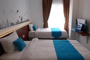 a hotel room with two beds and a window at Cemerlang Inn in Palembang