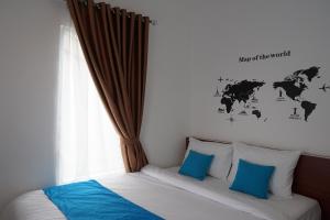 een slaapkamer met een bed met blauwe kussens en een raam bij Cemerlang Inn in Palembang