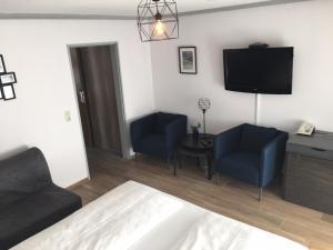 a living room with two blue chairs and a flat screen tv at Hotel KRONE Kressbronn am Bodensee in Kressbronn am Bodensee