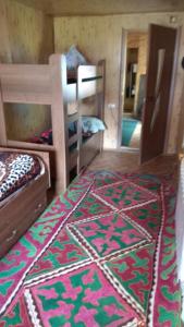 a room with two bunk beds and a rug at Ala-Kul guesthouse in Altyn-Arashan in Karakol