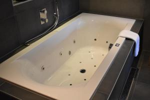 a large bath tub in a bathroom with a tile floor at Hotel De Vrouwe van Stavoren in Stavoren