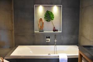 a bath tub in a bathroom with a plant on the wall at Hotel De Vrouwe van Stavoren in Stavoren