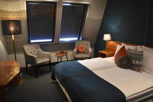 a hotel room with a bed and a chair at Hotel De Vrouwe van Stavoren in Stavoren