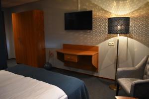 a hotel room with a bed and a tv and a chair at Hotel De Vrouwe van Stavoren in Stavoren